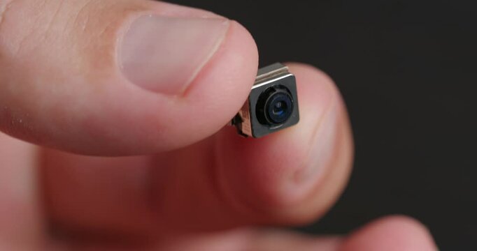 Miniature camera with tiny lens in hand, showcasing its intricate details and technology.