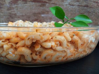 A dish of steamed macaroni sprinkled with cheese in a glass bowl.