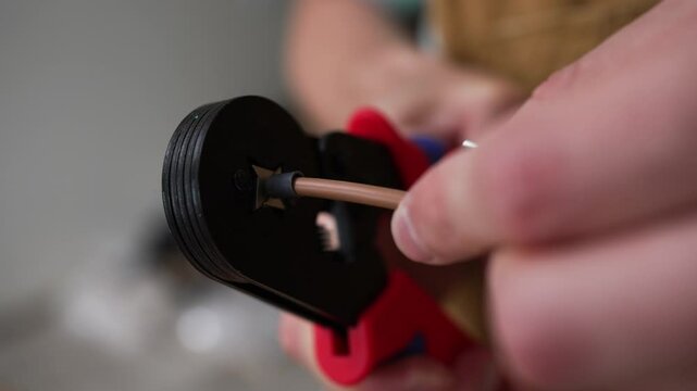 Skilled electrician performing precise wire crimping using specialized crimping tool, carefully connecting electrical components with professional expertise and technical precision