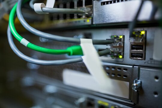Fototapeta Cluster of gray and green Ethernet cables are showing glowing status lights in metal switch panel