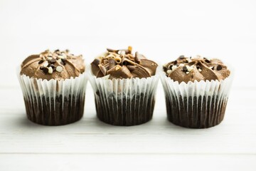 Chocolate cupcakes are showing in flat design on white table with liners, frosting and toppings