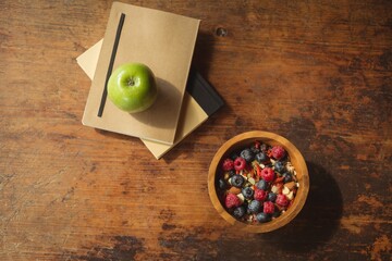 Directly above shot of berries in bowl by books