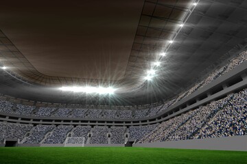 Fototapeta premium Soccer stadium interior is glowing under bright floodlights with green pitch, goalpost and stands