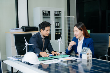 Engineers discuss solar panels and turbines in office, working on clean energy design, sustainable...