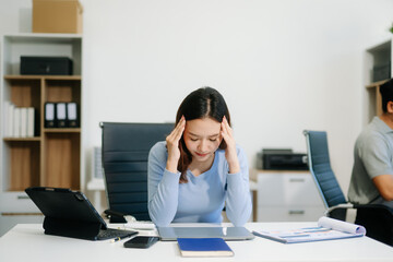 Asian woman feeling migraine head strain.Overworked businesswoman financier while working