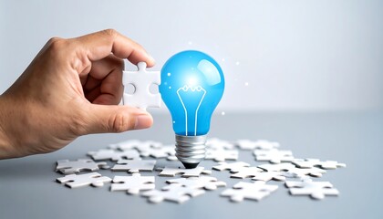 Hand placing puzzle piece next to glowing lightbulb