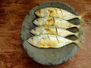 Raw spiced mackerel or ikan kembung in a stone mortar ready to be cooked.