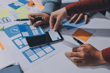 UX UI designer testing prototype on a phone, discussing and brainstorming on wireframes for a...