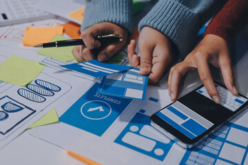 UX UI designer testing prototype on a phone, discussing and brainstorming on wireframes for a...