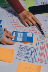 UX UI designer testing prototype on a phone, discussing and brainstorming on wireframes for a...