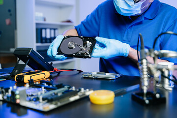 Hard disk drive on the technician's desk and a computer motherboard as a component. the concept of...