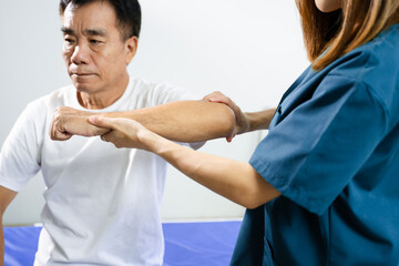 Female physiotherapist supports arm movement exercise for senior male patient during...