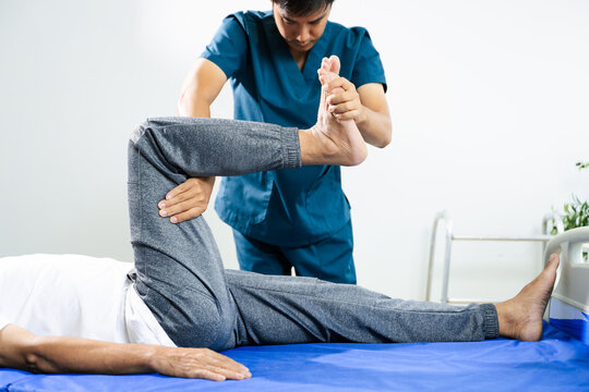 Physiotherapist assists patient with leg and ankle movement therapy during recovery session. Medical care, mobility training, and muscle rehabilitation