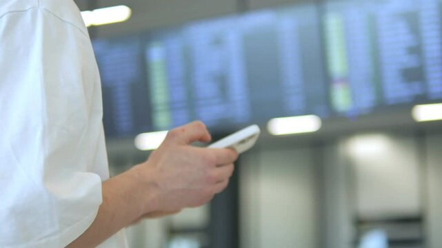 Person is holding a cell phone in front of a large screen with a lot of information on it