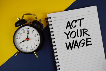 Act Your Wage text written on notepad with alarm clock on blue background