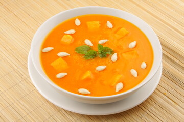 Healthy organic pumpkin seed soup served in white ceramic bowl.