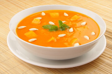 Healthy vegan diet meal-  delicious organic pumpkin cream soup, topped with pumpkin seeds and bread.