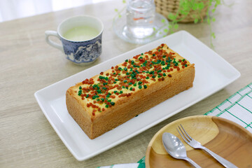 Sweet tasty cake with tea cup and wooden plate on wooden table