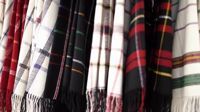 Row of patterned scarves, with visible fringes, hanging down
