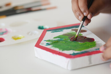 Fototapeta premium Child painting on a small canvas in a creative space
