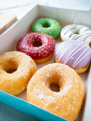 Donuts with different colorful icing designs arranged in a box.