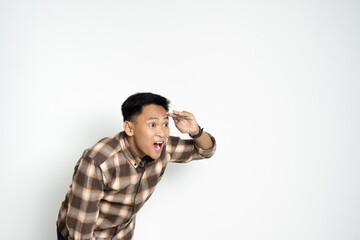 A cheerful young man wearing a plaid shirt looks forward with enthusiasm while indoors. The image features bright expressions, conveying happiness, anticipation, and fun.