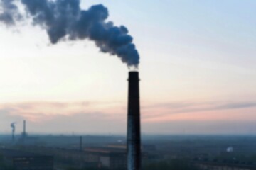 Industrial smokestack at dawn over cityscape