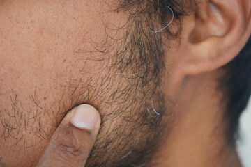 Close-up view of a man touching his facial hair