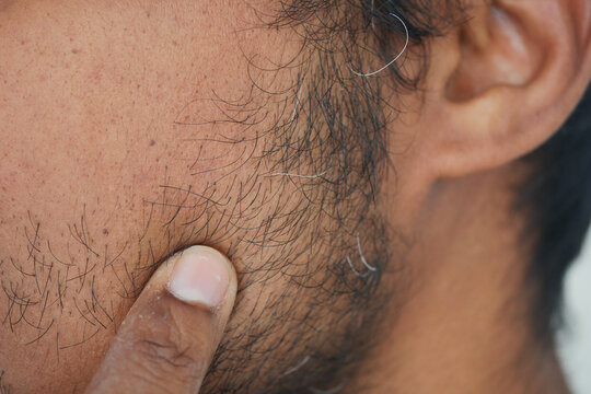 Close-up view of a man touching his facial hair - Powered by Adobe