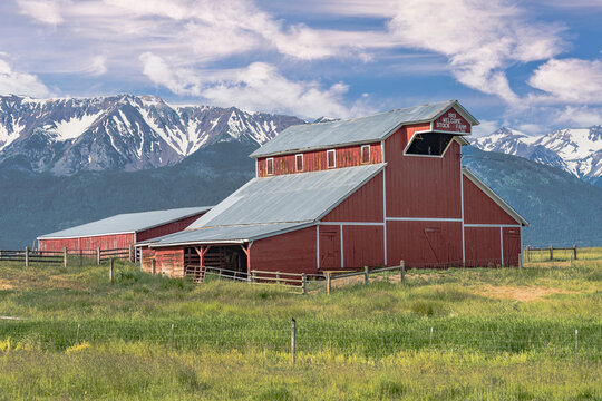 Iconic wooden red barn in Eastern Oregon with the Cascade Mountains in the background