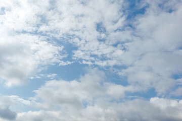 Fototapeta premium Scattered cumulus clouds drifting across a partly cloudy sky with visible blue areas and soft natural daylight atmosphere.