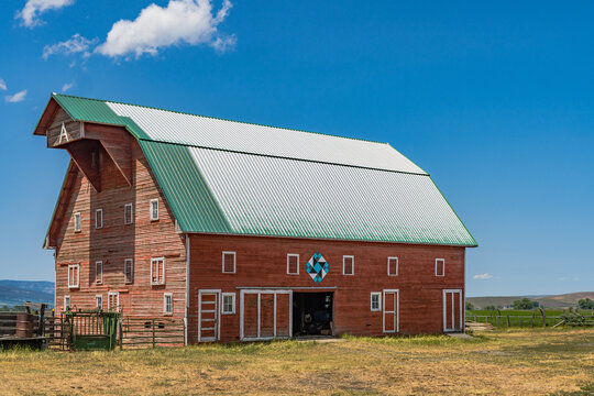 Iconic wooden red barn in Eastern Oregon with the Cascade Mountains in the background