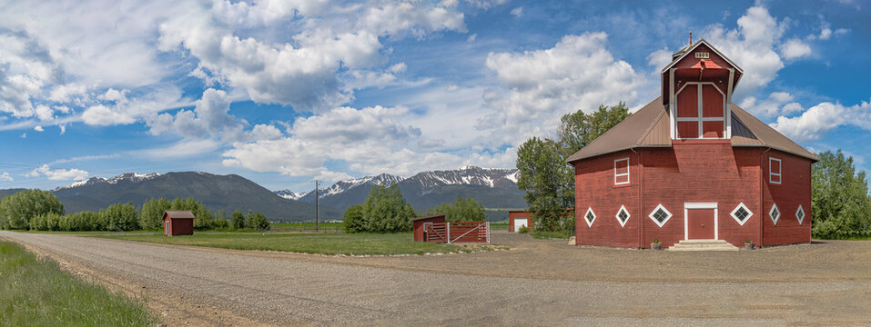 Iconic wooden red barn in Eastern Oregon with the Cascade Mountains in the background