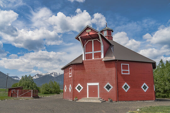 Iconic wooden red barn in Eastern Oregon with the Cascade Mountains in the background