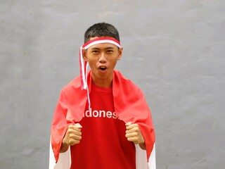 Indonesian young boy in red outfit and red white headband shouted excitedly during Indonesia...
