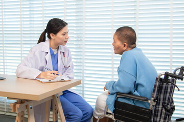 Female doctor consulting senior patient across table, pointing at laptop screen while discussing...
