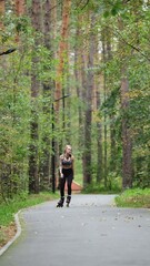 Obraz premium Attractive blonde feels free and light while rollerblading in city park in summer. Stunning Caucasian woman with beautiful figure uses roller skates for outdoor sports.