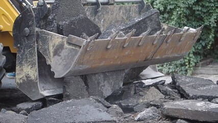 Heavy machinery removes broken asphalt from the road