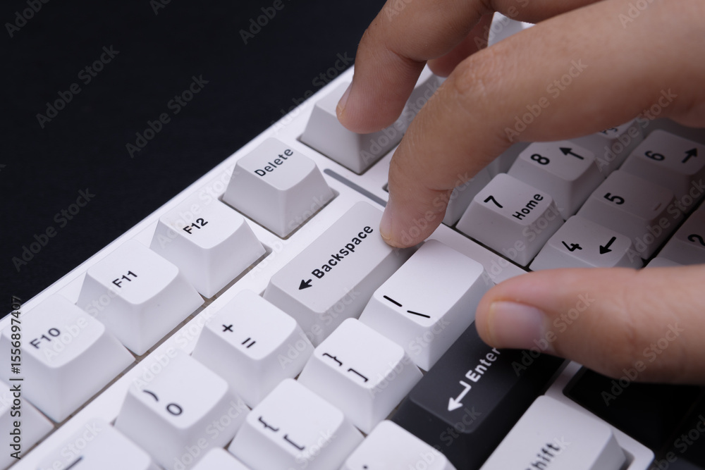Poster modern minimalist close-up photograph of finger on backspace key white keyboard for tech visuals edi