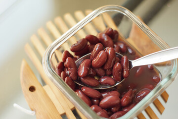 Cooked red kidney beans in a glass container with a spoon, perfect for dessert, healthy recipes, or...