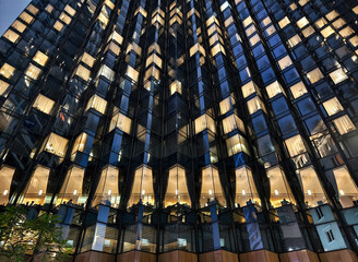 A tall building with many windows is beautifully lit up at night