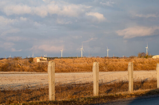 A group of wind turbines standing on open field.