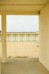 Blue and yellow building in the sand with doors
