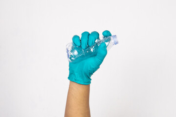 Hand wearing work gloves is holding an empty plastic bottle isolated on white background