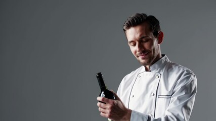 Chef presenting a wine bottle in a modern kitchen during a culinary demonstration