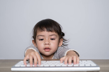 A focused child interacts with a keyboard, showcasing curiosity and engagement with technology in a minimalistic setting.