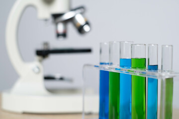 A close-up of test tubes filled with colorful liquids beside a microscope, emphasizing scientific experimentation and research.