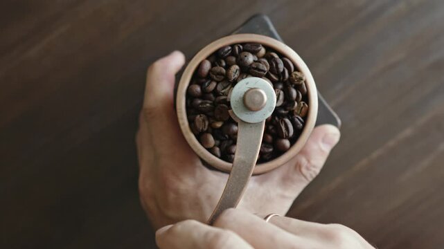 Grinding of aromatic coffee beans with a manual coffee grinder. Smooth rotation of the camera. Top view