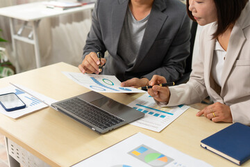 Two business professionals analyzing financial charts at desk