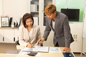 Two colleagues discussing business charts in office setting